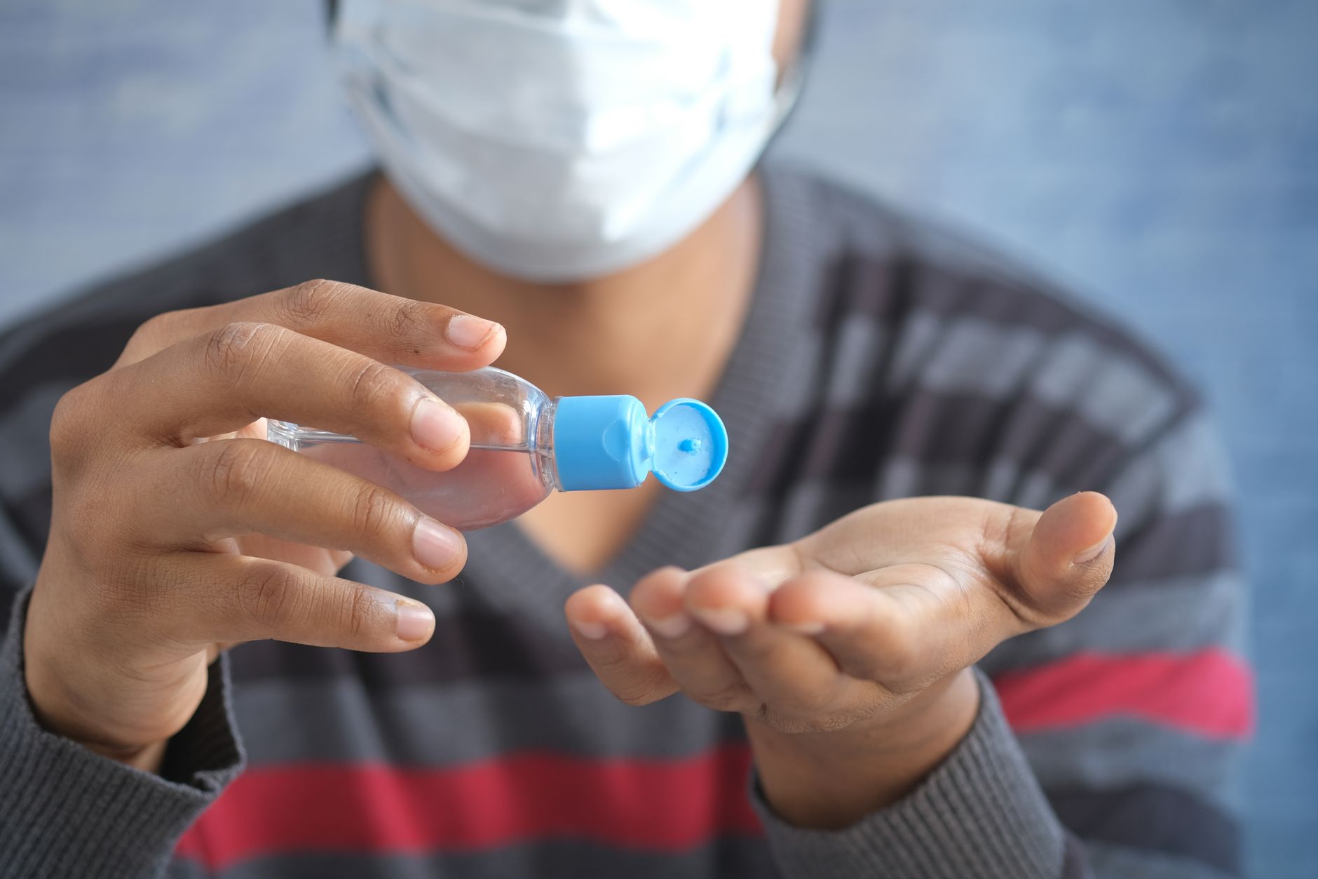 Person applying hand sanitizer from a small bottle