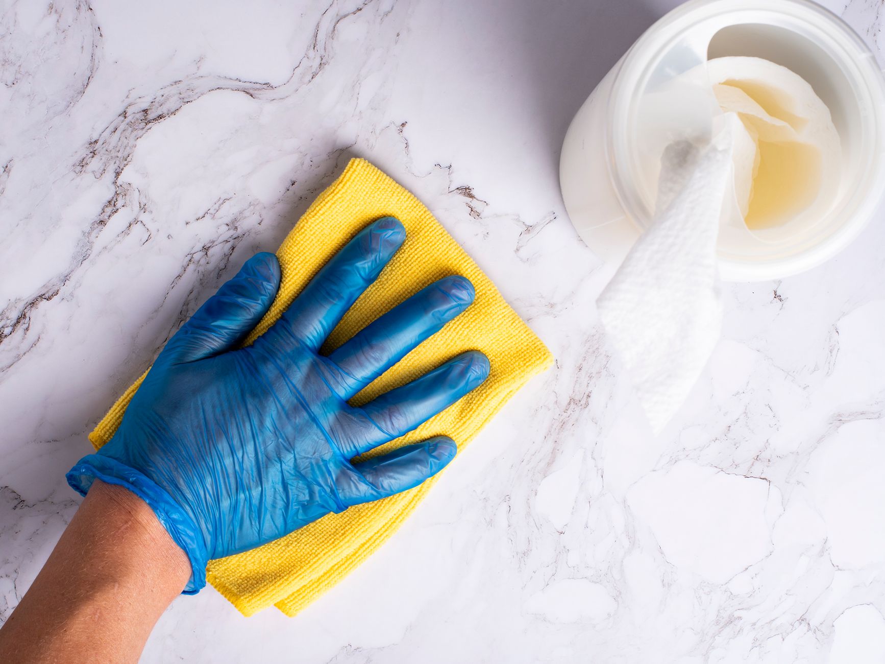 Gloved hand wiping a surface with a disinfectant cloth