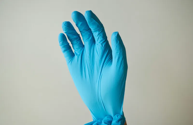 Hand wearing a blue nitrile glove