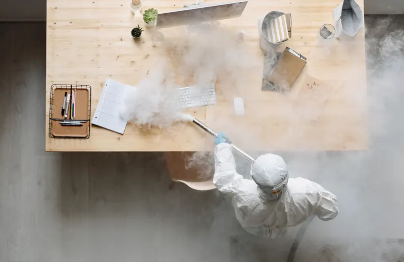 Worker in a protective suit disinfecting a commercial workspace